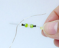 將珠子串在串線片上，線穿過穿線片的針眼.
