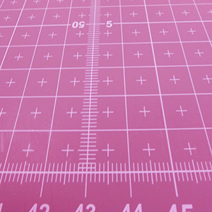 粉紅色面料
中間另有雙軌道輔助刻度，讓切割墊不論從哪個方向使用, 都可以馬上對齊裁切.